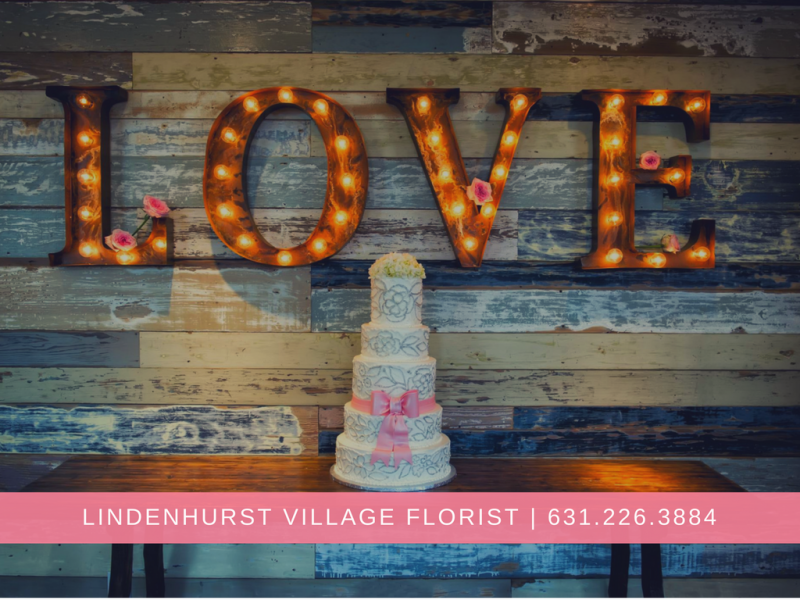 Marquee letters spelling LOVE above a pastel cake at Lindenhurst Village Florist, with store name and phone number below