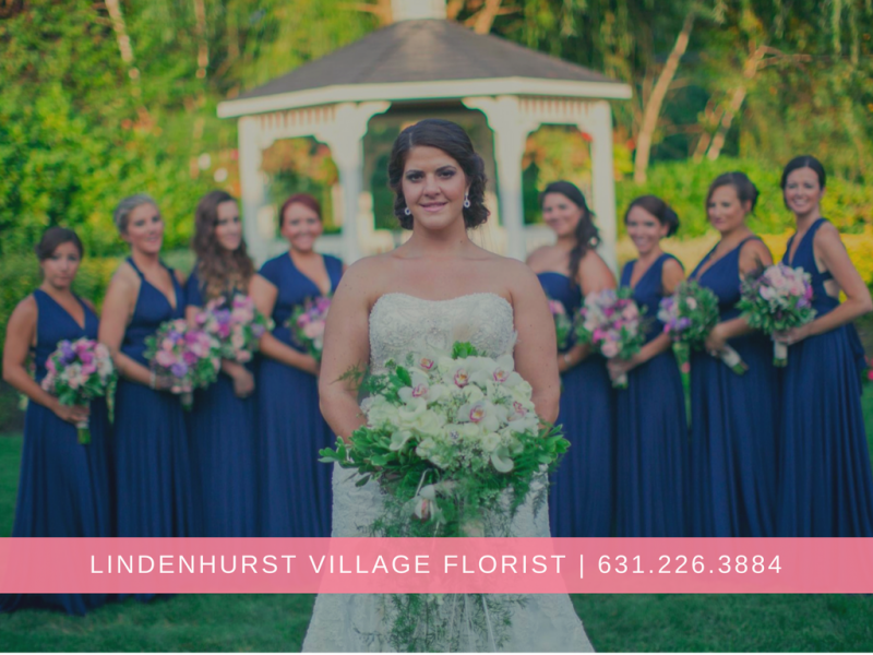 Bride holding bouquet with bridesmaids in navy dresses outdoors, with florist banner at bottom