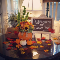 Welcome fall sign with pumpkins, sunflowers, and autumn leaves on a decorated table