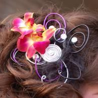 Pink and yellow flowers with white swirls in a brown hair updo