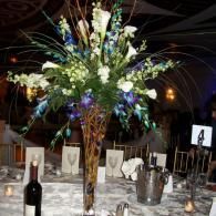 Elegant banquet table with tall mixed-flower centerpiece, candles, wine bottle, and table number 4