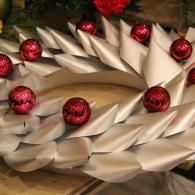 White paper wreath with red ornaments and pinecones on a Christmas tree.