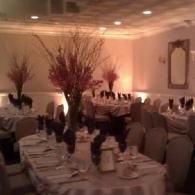 Elegant banquet hall with long tables set for a formal dinner, decorated with tall floral centerpieces.