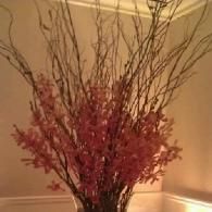 Tall vase with red and brown decorative branches against a beige wall