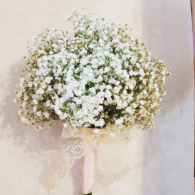 Large bouquet of white baby’s breath in a pale vase against a soft beige wall