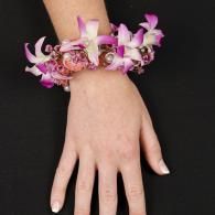 Hand with pink-and-white floral bracelet on a black background