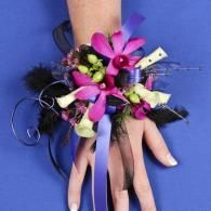 Hand wearing a purple floral and feather bracelet with dangling ribbons on a blue background