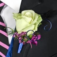 Boutonniere with pale green rose, purple flowers, and black ribbon on a black suit jacket
