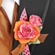 Pink and orange floral boutonniere with ribbon and polka-dot accent on a suit lapel