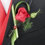 Red rose boutonniere with green ribbon and white bud on a black suit lapel
