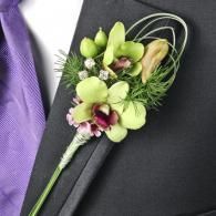 Green and purple boutonniere pinned to a dark suit with a lavender tie