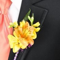 Yellow flower boutonniere on a black suit lapel with a pink tie
