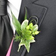 Black suit lapel with green boutonniere and pink tie accent