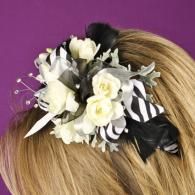 Black and white floral hair accessory with striped ribbon on blonde hair against purple background