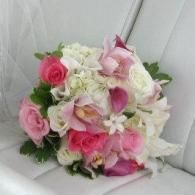 Pink and white rose bouquet with white flowers, arranged against a white chair back