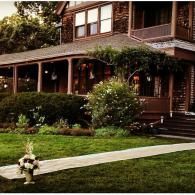 Two-story brick house with a front porch, lawn, walkway, and flower bed