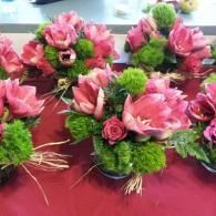 Pink and green floral arrangements on a table with red tablecloth