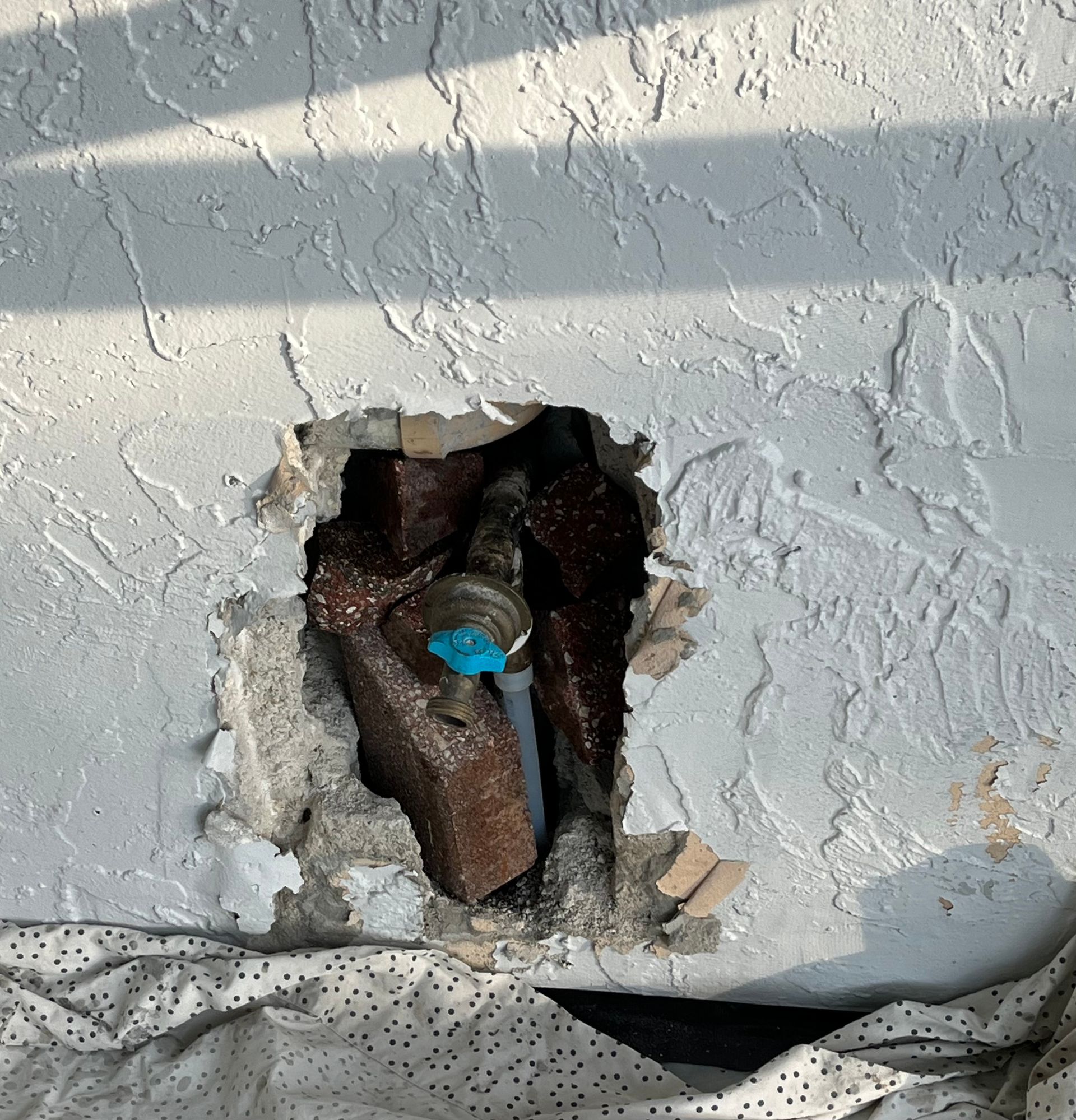 A hole in a wall with a blue valve in it