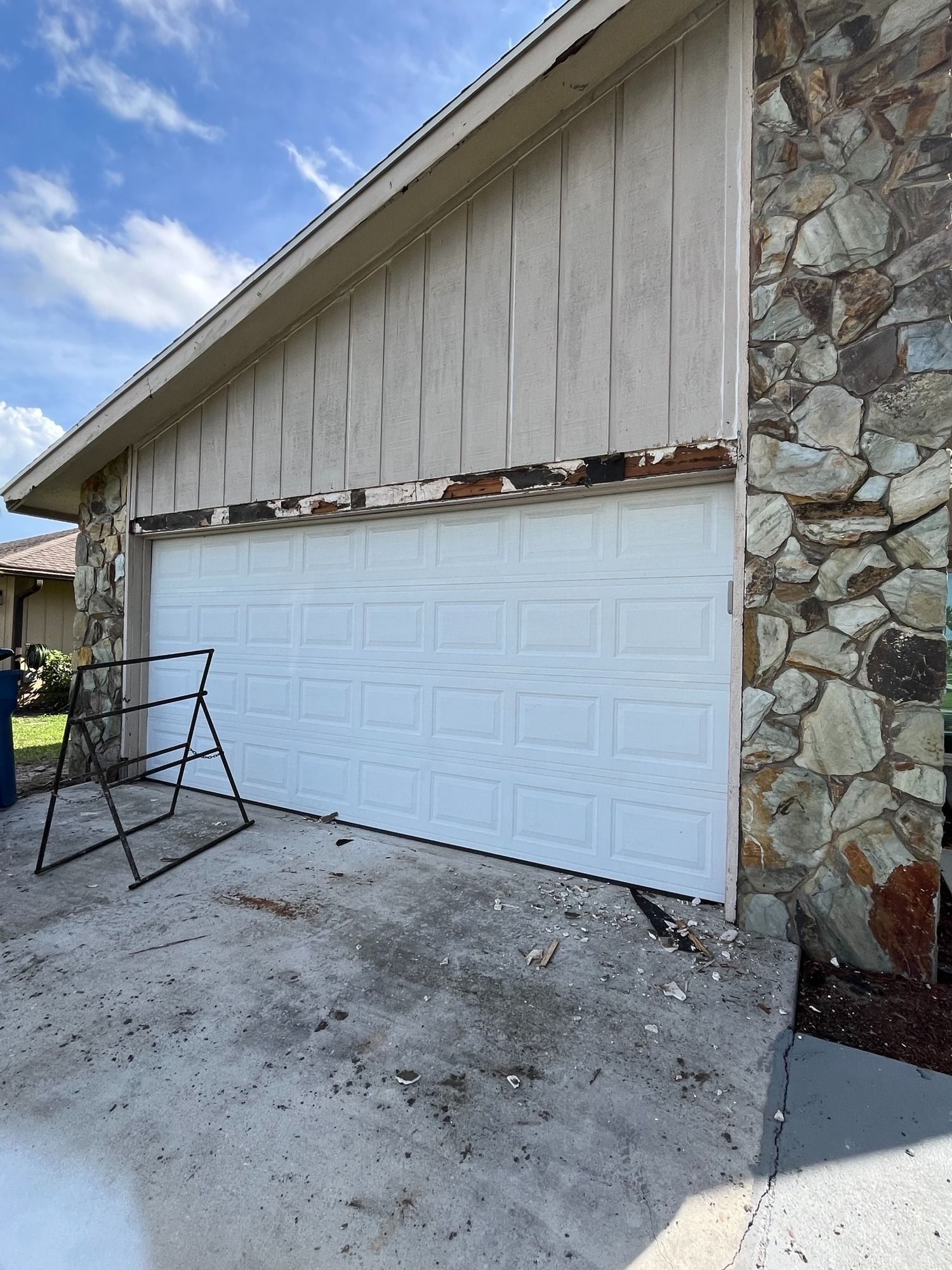 A white garage door is being removed from a stone building.
