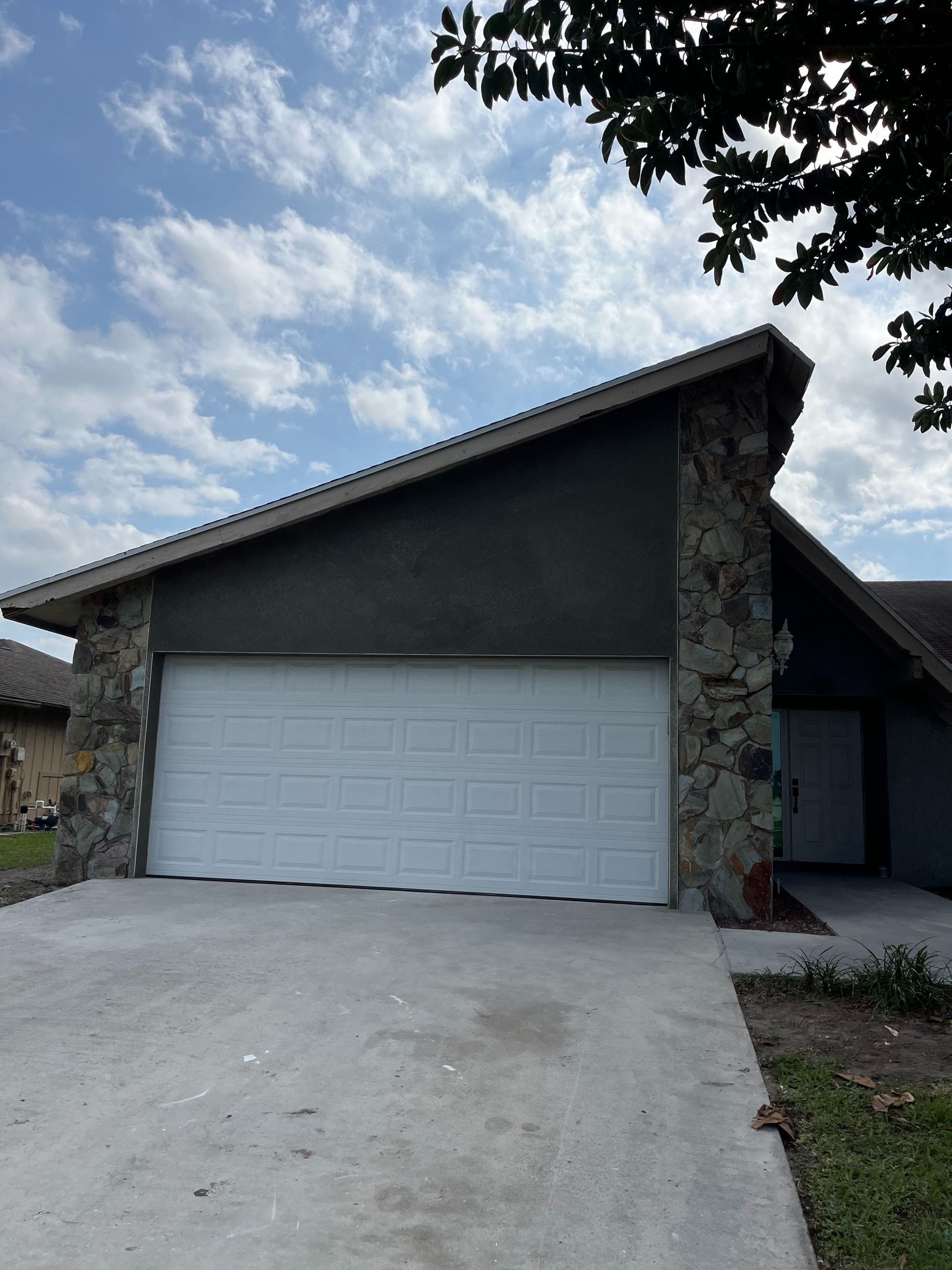 A house with a stone wall and a white garage door