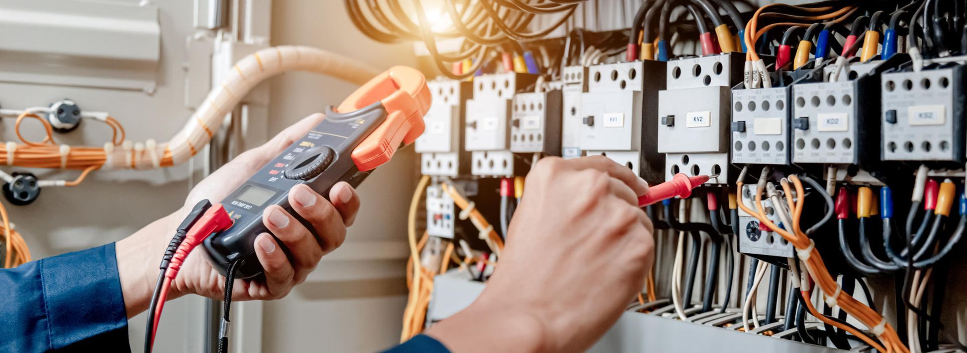 Ein Elektriker überprüft mit einem Multimeter die elektrische Verkabelung in einem Schaltschrank.