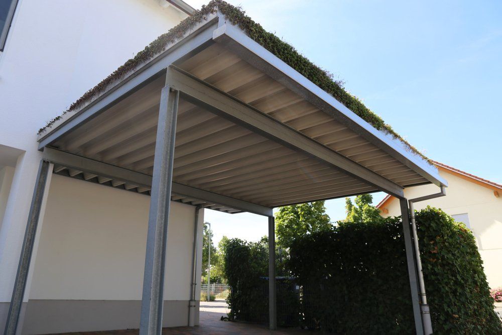 A Carport is Sitting in Front of a White House — Goulburn Roofing In Goulburn, NSW
