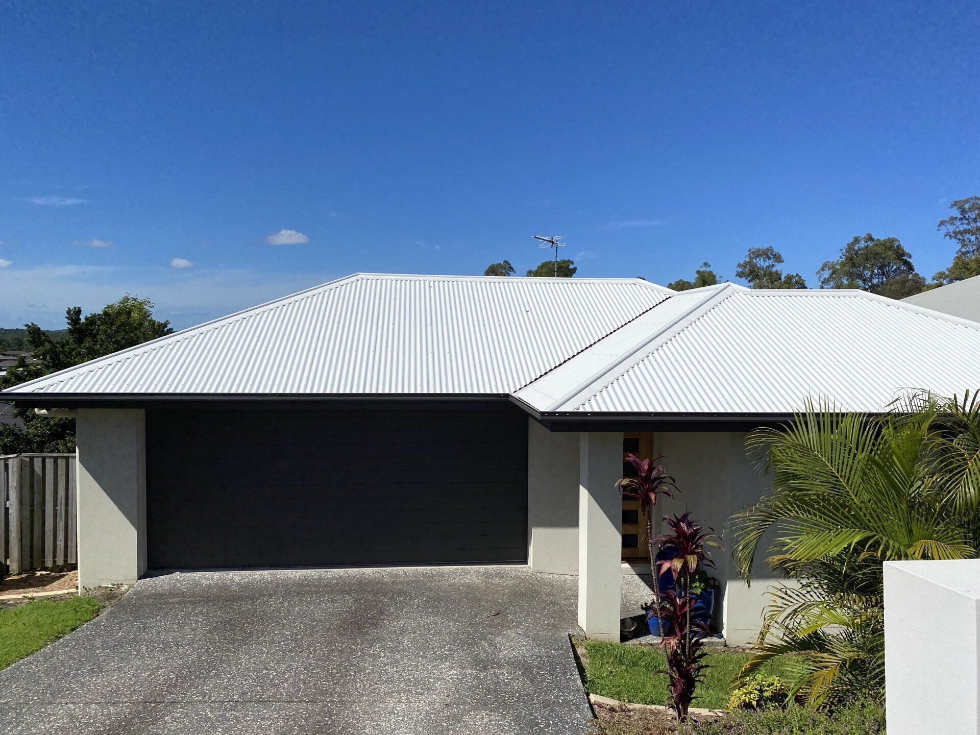A Before and After Picture of a Brick House With a Red Roof — Goulburn Roofing In Goulburn, NSW