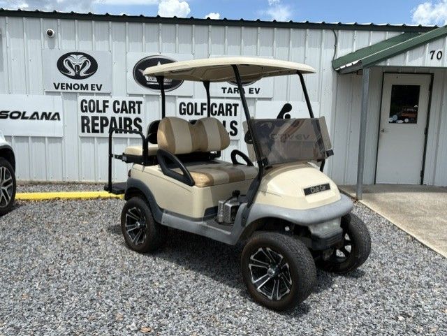 Maroon and black golf cart parked on gravel outside a golf cart repair shop