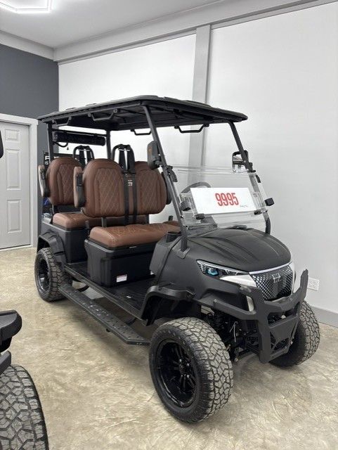 Black four-seat utility vehicle with roof and brown seats parked indoors in a garage.