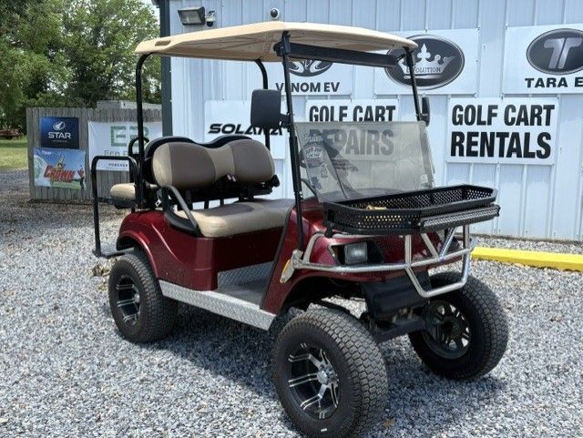 Maroon golf cart parked on gravel outside a golf cart rental building
