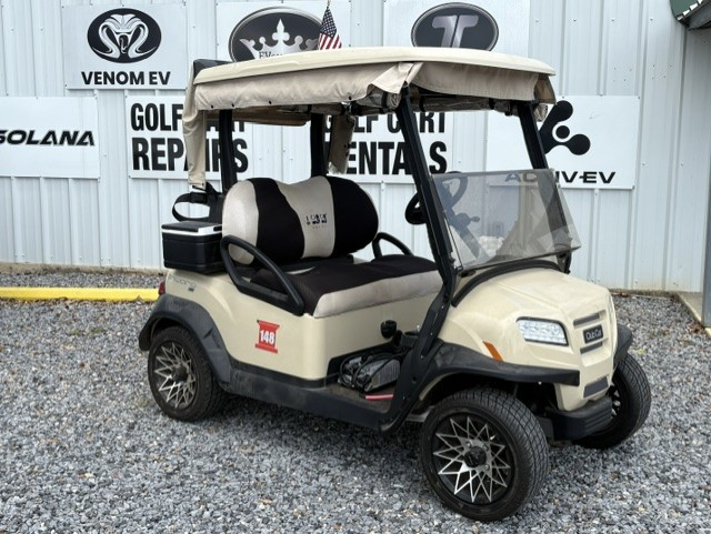 Maroon and black golf cart parked on gravel outside a golf cart repair shop