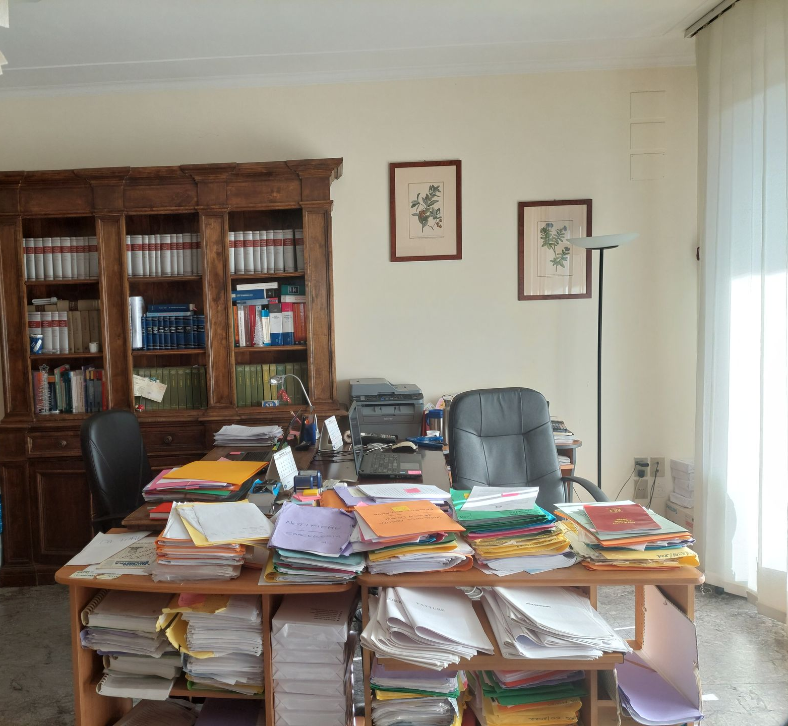 Due persone sedute a un tavolo di legno: una indica un documento, l'altra scrive con una penna.