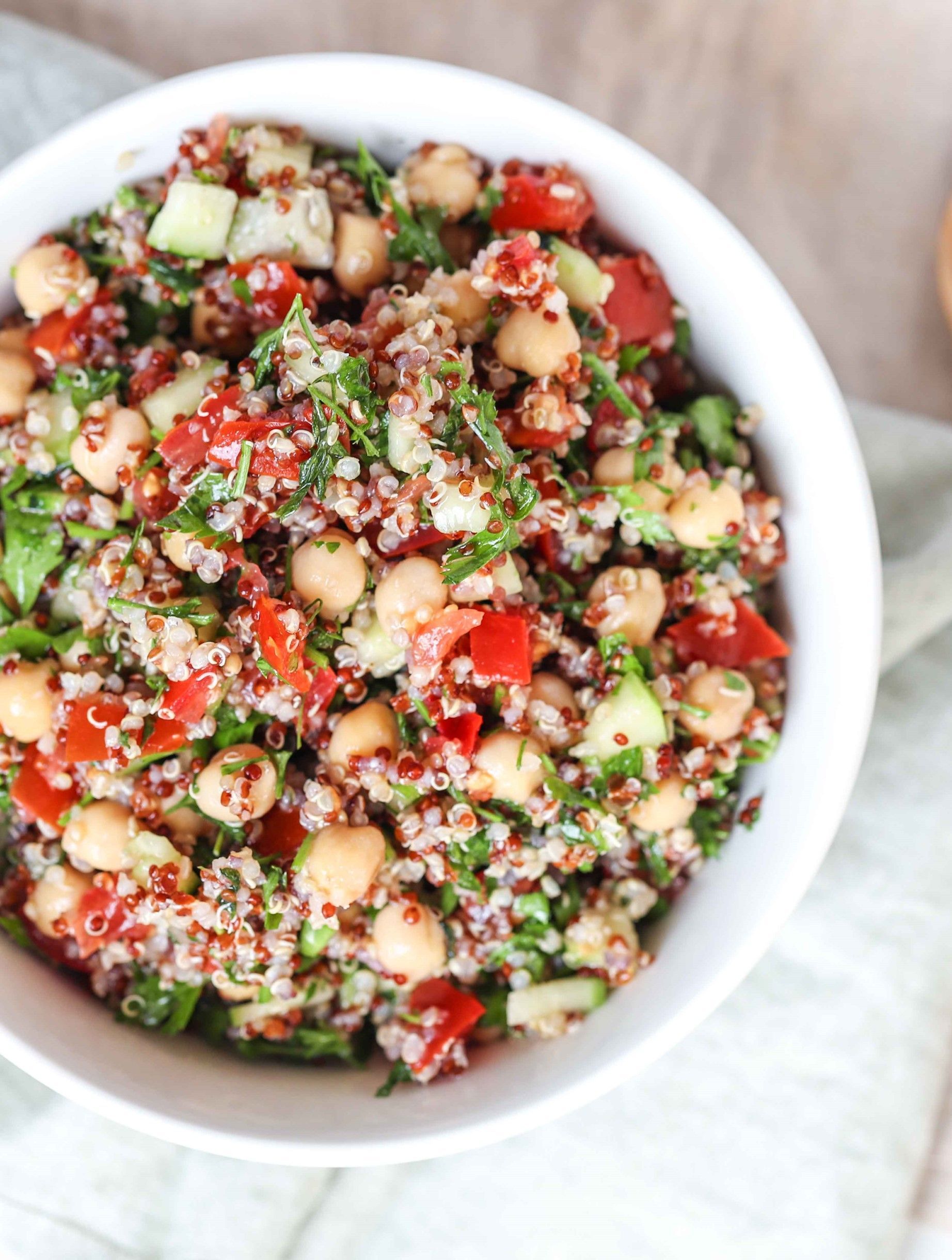 A bowl of salad with chickpeas , quinoa , tomatoes and cucumbers
