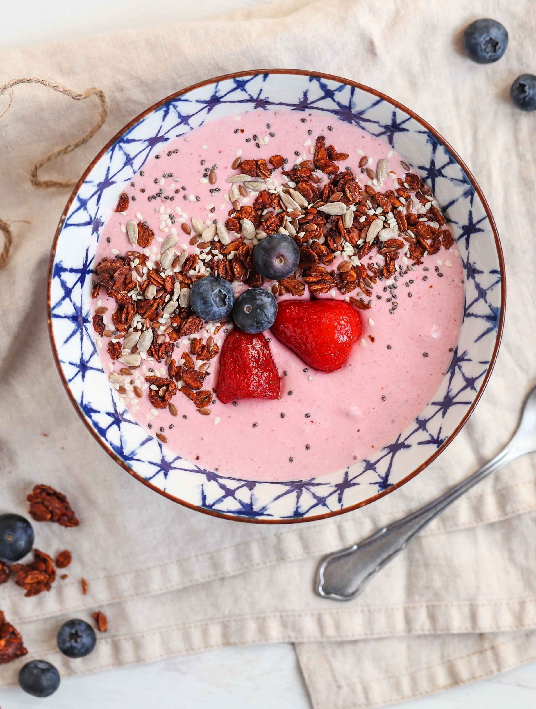 A bowl of yogurt with strawberries and blueberries on top