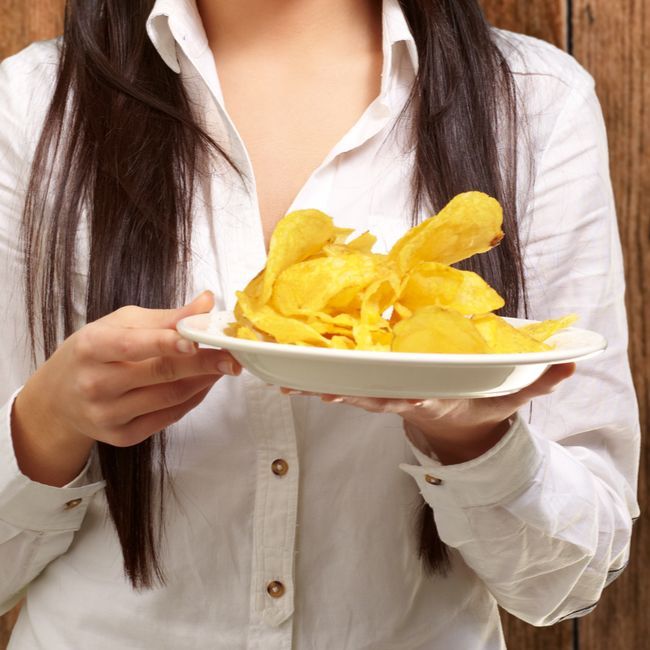 A woman in a white shirt is holding a plate of potato chips
