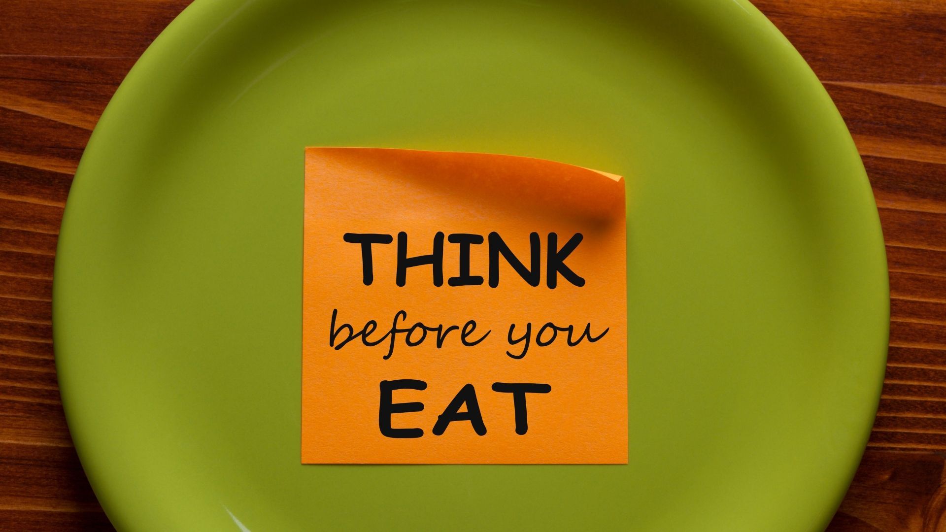 Round green plate on a wooden table, with an orange sticky note attached to the center of the plate