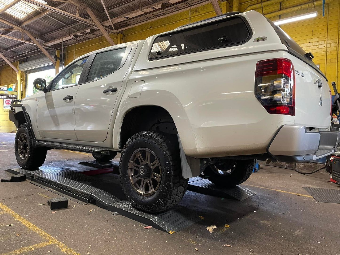 Mechanic Inspecting Raised Pickup Truck In Workshop Garage