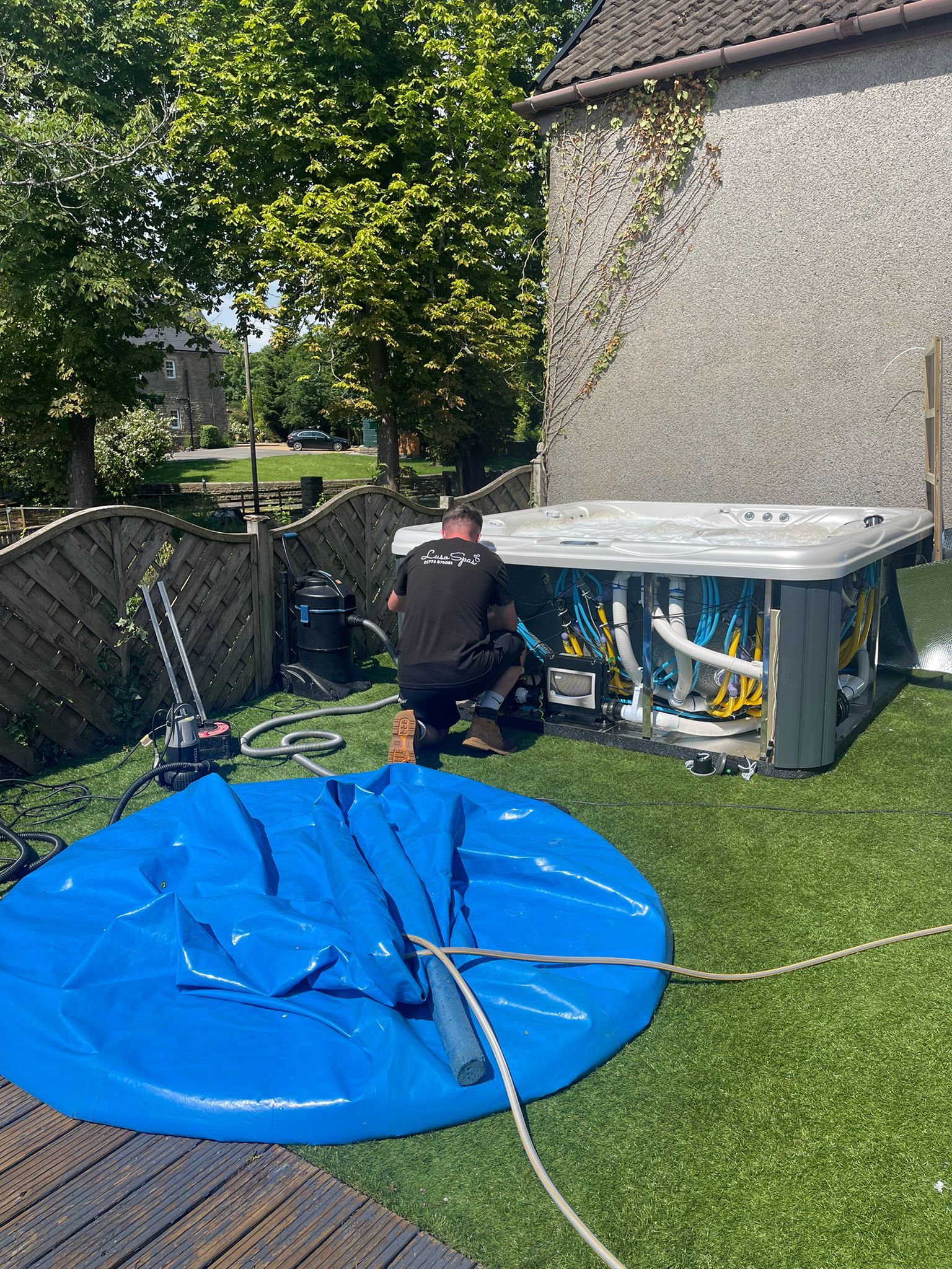 A man is working on a hot tub in a backyard.