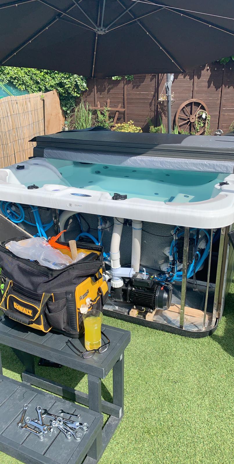 A hot tub is being built in a backyard under an umbrella.