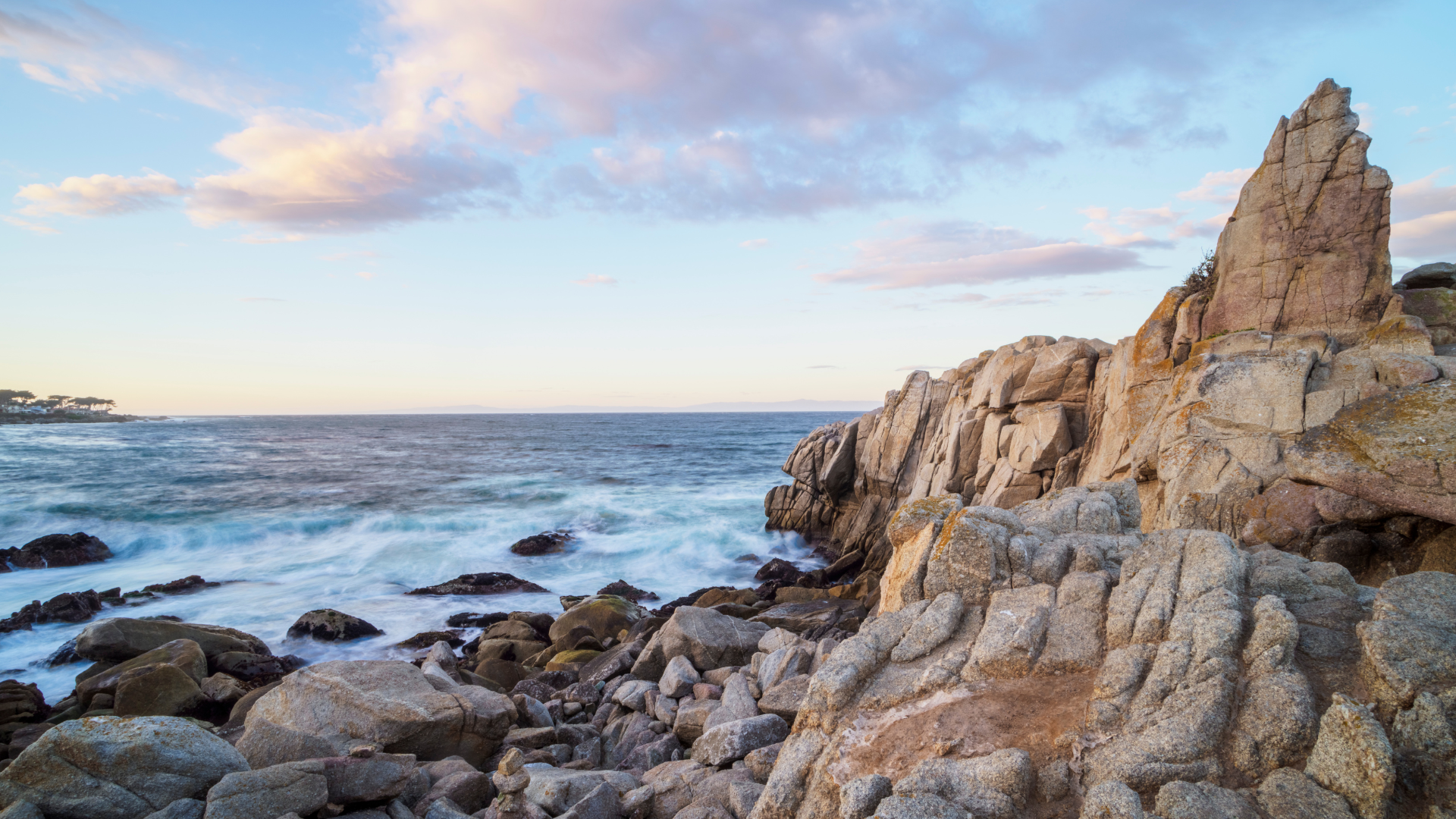Coastal house perched on rocky cliffs with ocean view; golden sunlight.