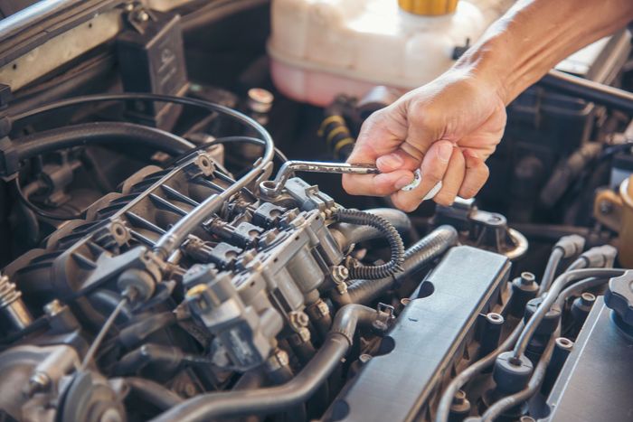 a man is working on the engine of a car with a wrench .