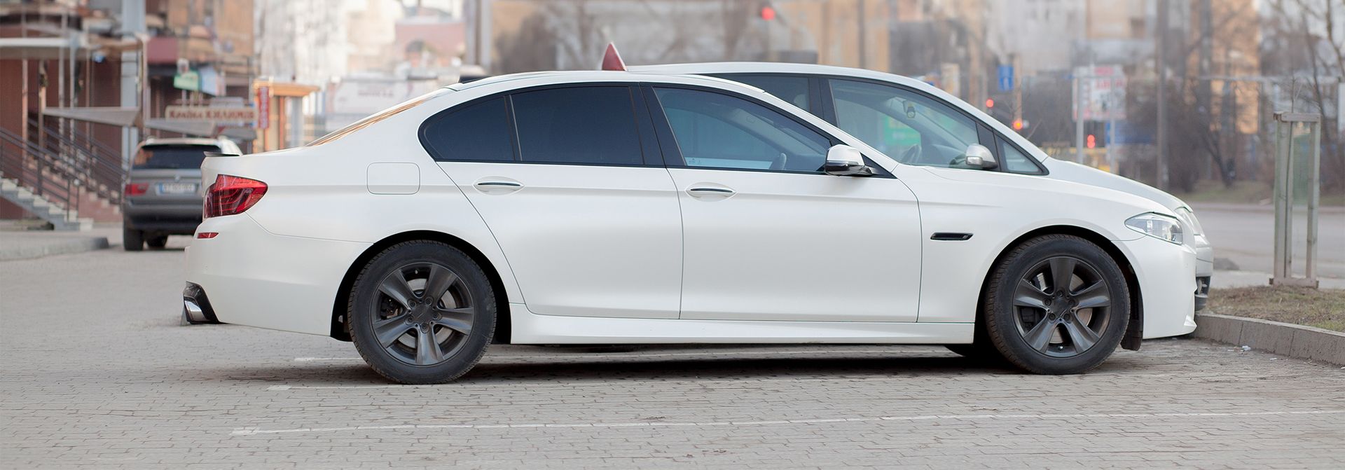 a white car is parked on the side of the road in a parking lot .