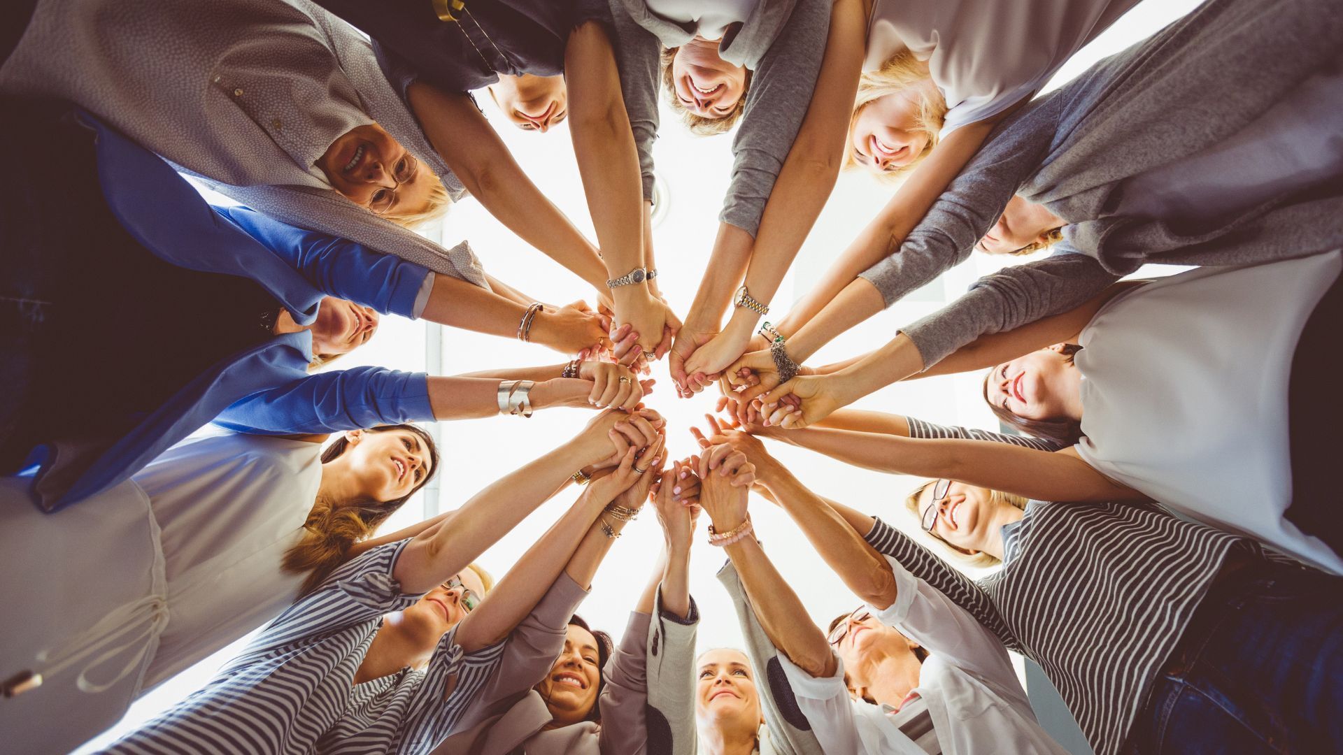 A group of people are putting their hands together in a circle.