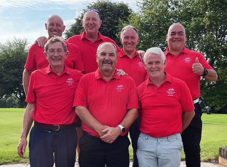 A group of men in red shirts are posing for a picture.