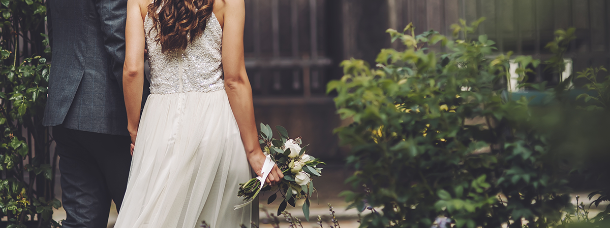 Couple walking, woman in wedding dress holding bouquet.