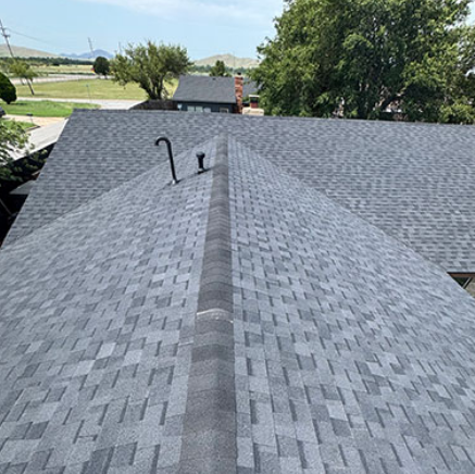 Gray shingled roof with a ridge vent and two black roof vents under a clear sky