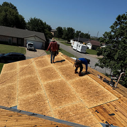 Workers installing plywood roofing on a house roof in a suburban neighborhood