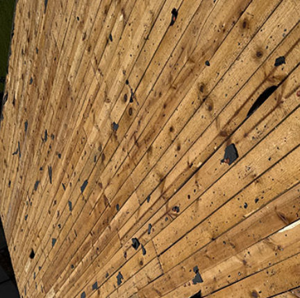 Close-up of a weathered wooden wall with diagonal planks, knots, and dark stains.