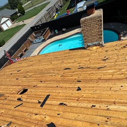 Damaged shingle roof with debris overlooking a backyard pool and brick chimney
