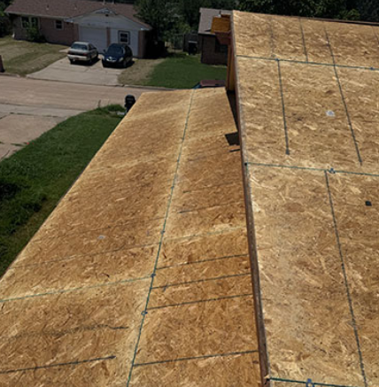 Roof under construction with plywood sheathing in a suburban neighborhood.